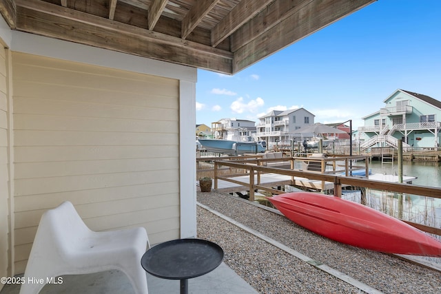 balcony featuring a boat dock, a water view, boat lift, and a residential view