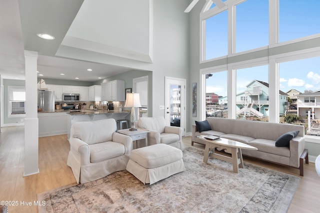 living room featuring light wood-type flooring, baseboards, and recessed lighting