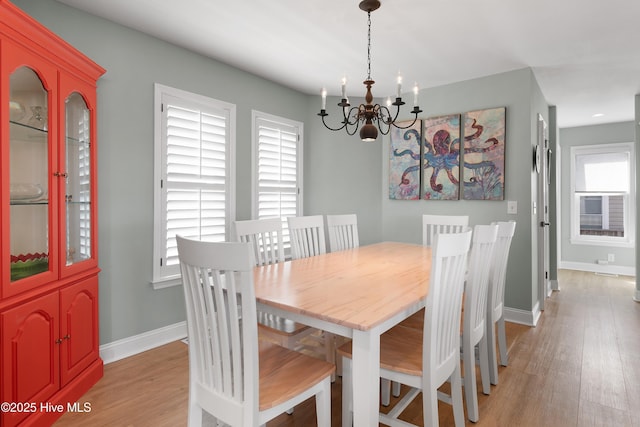 dining room featuring light wood-type flooring, baseboards, and an inviting chandelier