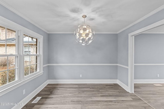 unfurnished dining area featuring crown molding, hardwood / wood-style floors, and a chandelier