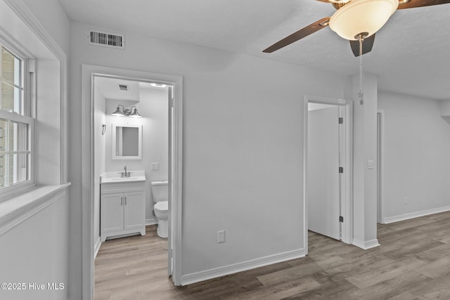 unfurnished bedroom featuring ensuite bathroom, sink, and light wood-type flooring