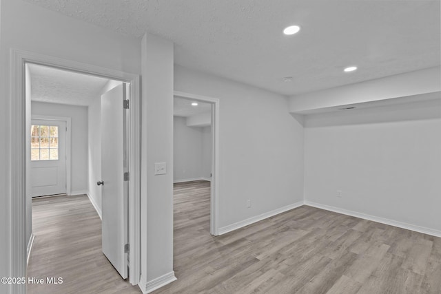 unfurnished room with light hardwood / wood-style flooring and a textured ceiling