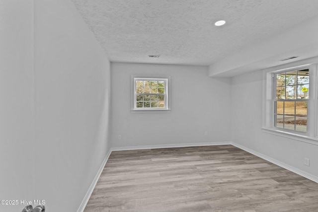 empty room with a textured ceiling and light wood-type flooring