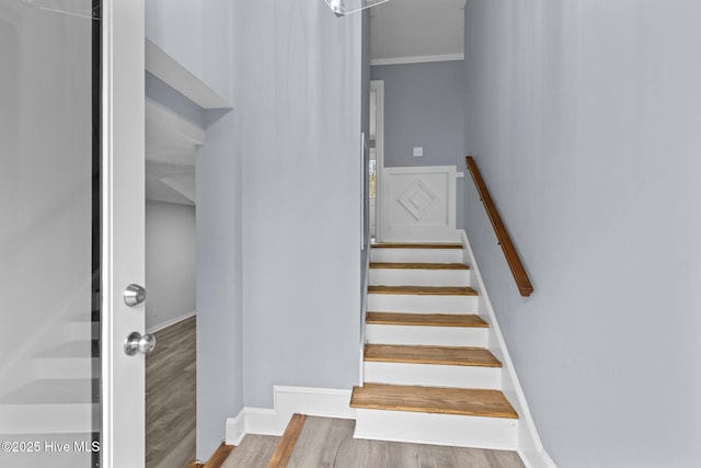 stairway featuring ornamental molding and wood-type flooring