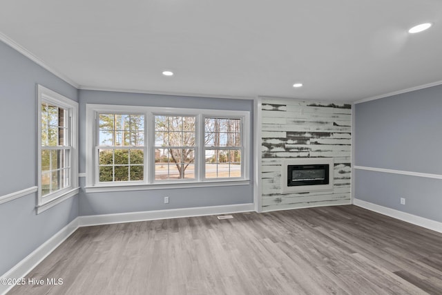 unfurnished living room with crown molding, a large fireplace, and wood-type flooring