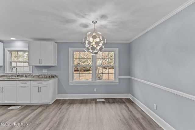 kitchen featuring white cabinetry, sink, pendant lighting, and light wood-type flooring