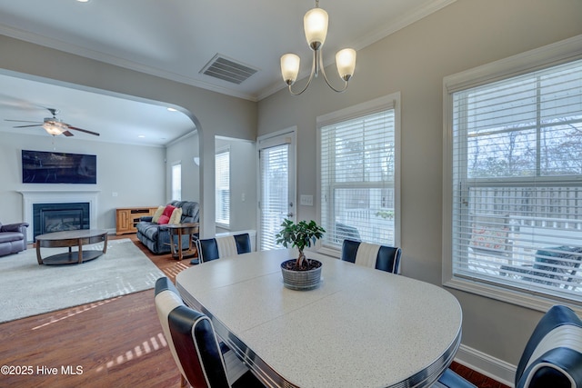 dining room with ceiling fan with notable chandelier, ornamental molding, and hardwood / wood-style floors