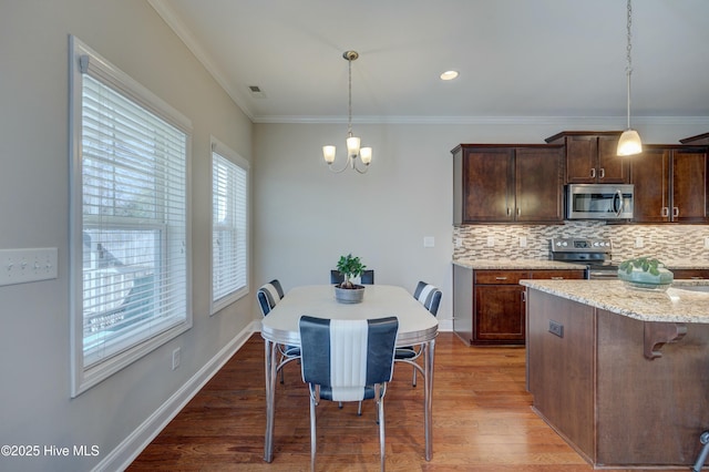 kitchen with a breakfast bar, stainless steel appliances, decorative light fixtures, and light stone countertops