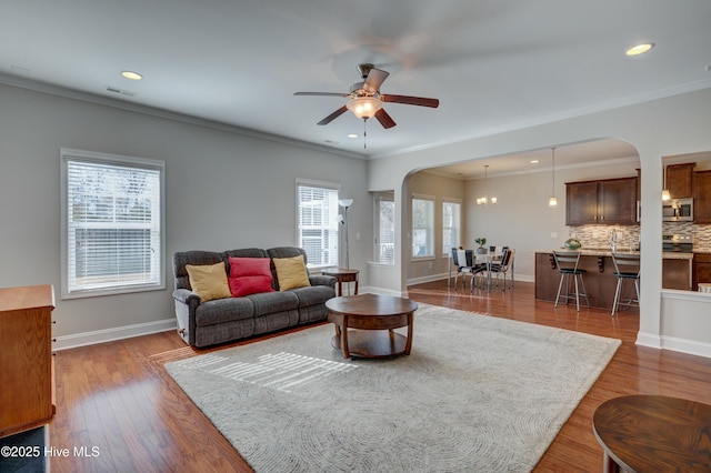 living room featuring ceiling fan, ornamental molding, and dark hardwood / wood-style flooring