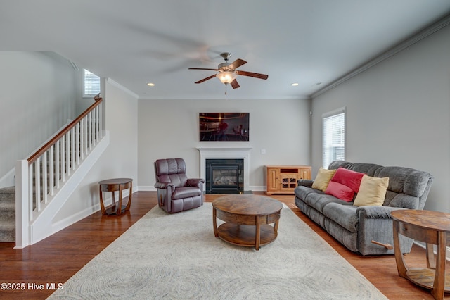 living room with crown molding, ceiling fan, and wood-type flooring