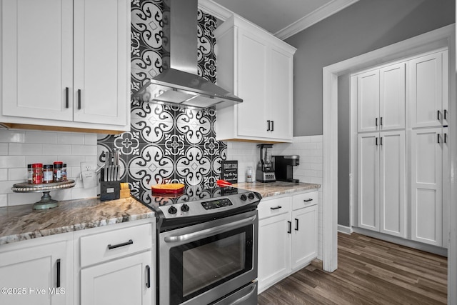 kitchen featuring white cabinetry, stainless steel range with electric stovetop, light stone counters, ornamental molding, and wall chimney range hood