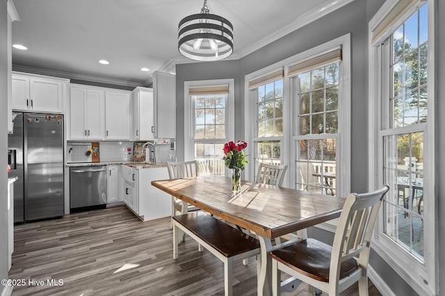 kitchen with appliances with stainless steel finishes, backsplash, white cabinets, crown molding, and light stone countertops