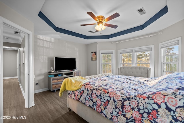 bedroom featuring dark hardwood / wood-style flooring, a raised ceiling, and ceiling fan