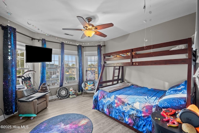 bedroom featuring multiple windows, wood-type flooring, and ceiling fan