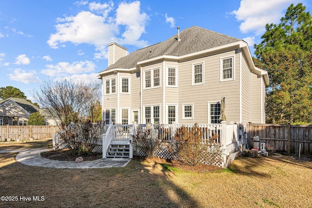 back of property with a deck and a lawn