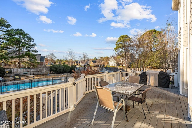 wooden terrace featuring area for grilling and a fenced in pool