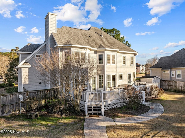 rear view of house featuring a yard, a deck, and a shed