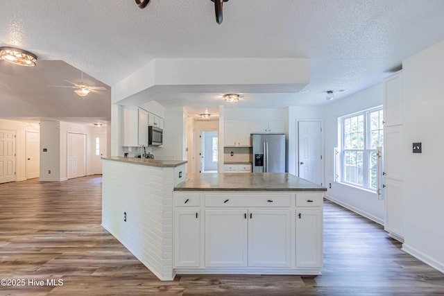 kitchen with appliances with stainless steel finishes, a textured ceiling, a ceiling fan, and dark wood-style floors