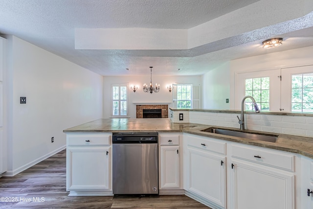 kitchen with dark wood finished floors, stainless steel dishwasher, a textured ceiling, and a sink