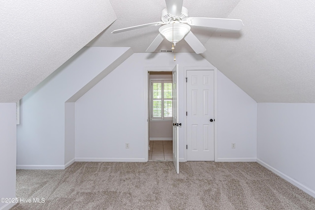 additional living space with ceiling fan, carpet, baseboards, a textured ceiling, and lofted ceiling