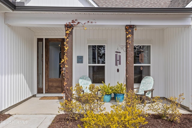 view of exterior entry featuring a shingled roof and a porch