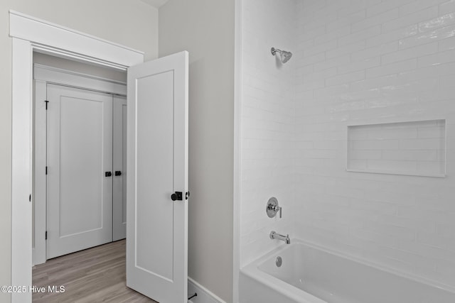 bathroom with tiled shower / bath combo and hardwood / wood-style flooring