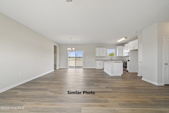 kitchen featuring white cabinetry, a center island, a notable chandelier, stainless steel appliances, and light wood-type flooring