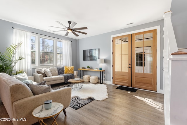 living area with baseboards, french doors, visible vents, light wood-style floors, and ceiling fan