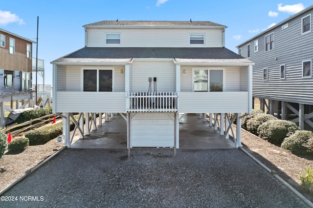 view of front of house with a carport, gravel driveway, and a shingled roof