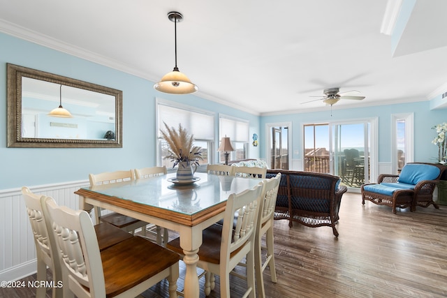 dining room with a wainscoted wall, ornamental molding, wood finished floors, and a wealth of natural light