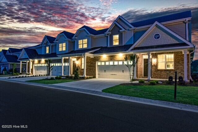 view of front of property featuring a garage, driveway, a front lawn, and stone siding