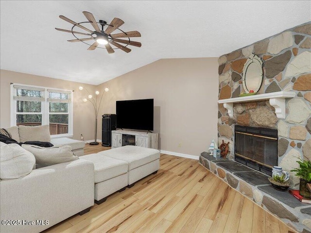 living room featuring ceiling fan, lofted ceiling, light wood-type flooring, and a fireplace