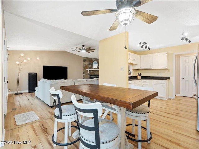 dining space featuring vaulted ceiling, ceiling fan, and light hardwood / wood-style floors