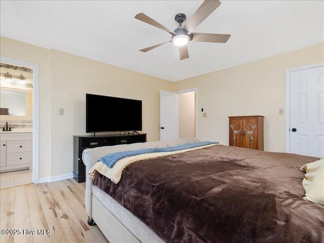 bedroom with ceiling fan, a textured ceiling, light hardwood / wood-style floors, and ensuite bath