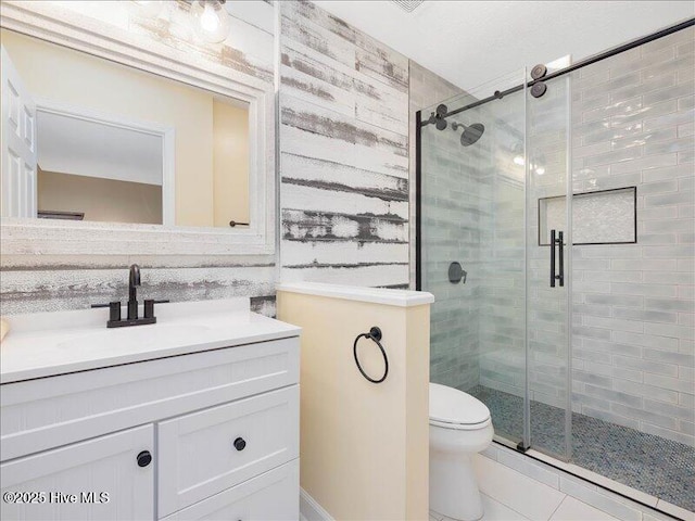 bathroom with tile patterned flooring, vanity, toilet, and walk in shower