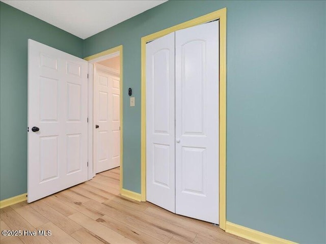 unfurnished bedroom with light wood-type flooring and a closet