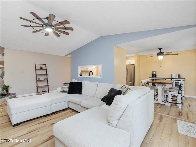 living room with ceiling fan, lofted ceiling, and light wood-type flooring