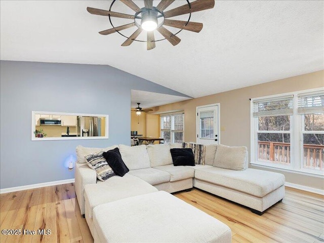 living room with ceiling fan, lofted ceiling, and light hardwood / wood-style floors