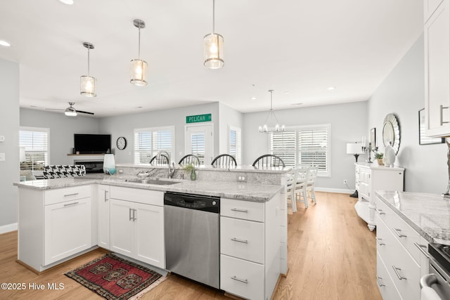 kitchen with light wood-style floors, appliances with stainless steel finishes, a sink, and ceiling fan with notable chandelier