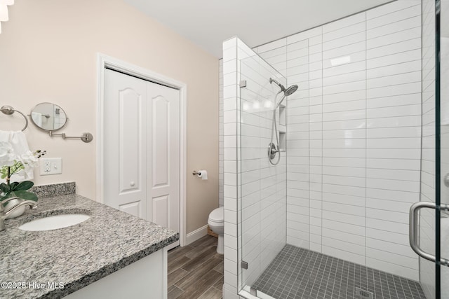 full bathroom featuring baseboards, toilet, wood finished floors, vanity, and a shower stall