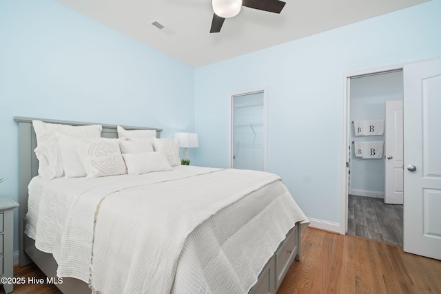 bedroom featuring baseboards, visible vents, a ceiling fan, wood finished floors, and a closet