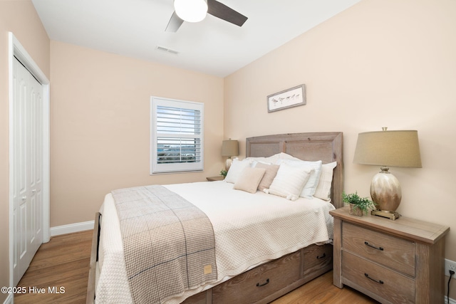 bedroom with light wood finished floors, a closet, visible vents, ceiling fan, and baseboards