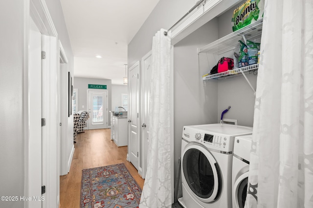 laundry area with laundry area, light wood-style flooring, baseboards, and washer and clothes dryer