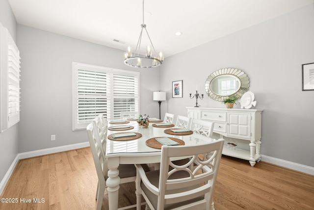 dining room featuring light wood finished floors, plenty of natural light, visible vents, and a chandelier