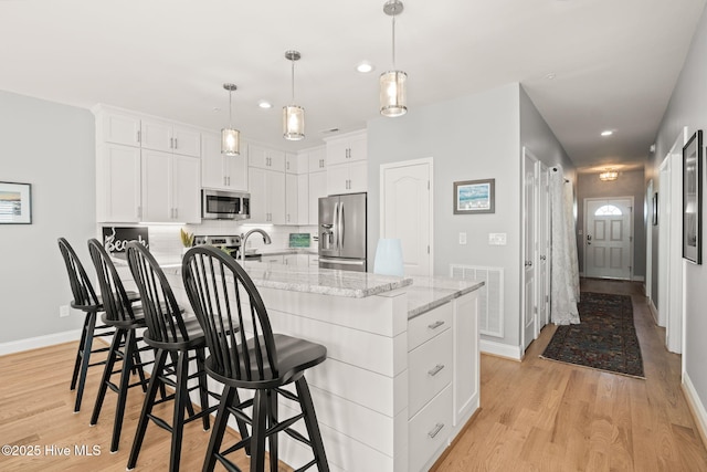 kitchen featuring light wood-style floors, white cabinetry, appliances with stainless steel finishes, and tasteful backsplash