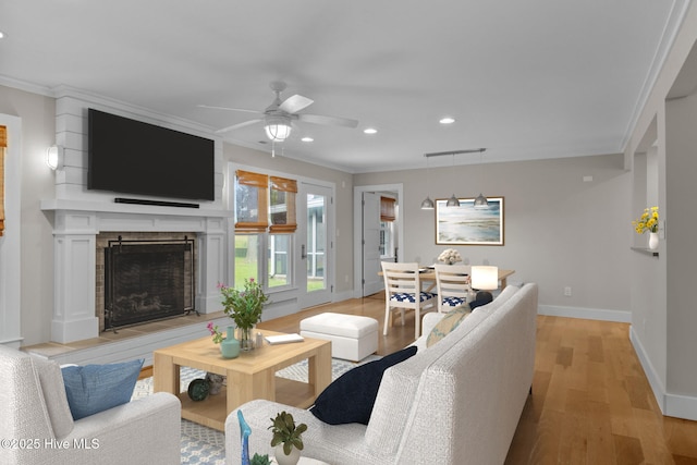 living room featuring crown molding, light hardwood / wood-style flooring, and ceiling fan