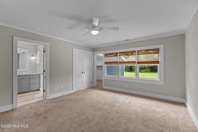 unfurnished bedroom featuring crown molding, light colored carpet, ensuite bathroom, and a closet