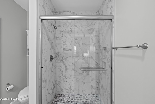 bathroom featuring a shower with shower door and toilet