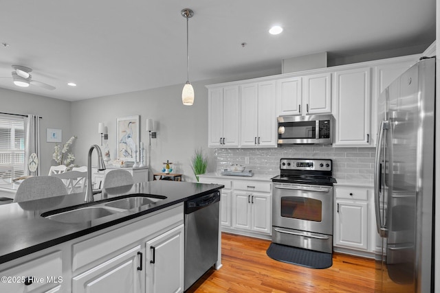 kitchen featuring white cabinetry, decorative light fixtures, sink, appliances with stainless steel finishes, and decorative backsplash