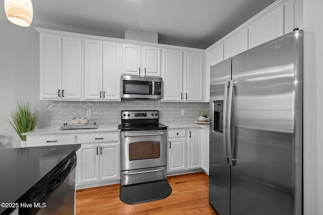 kitchen with appliances with stainless steel finishes, decorative backsplash, light hardwood / wood-style floors, and white cabinetry